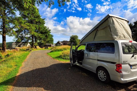 Campervan with pop-up roof, opened roof, mini camper Nissan NV200, camping on a farm, sunny