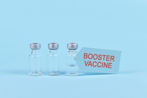 Corina virus booster vaccination concept with vial and syringe on blue background