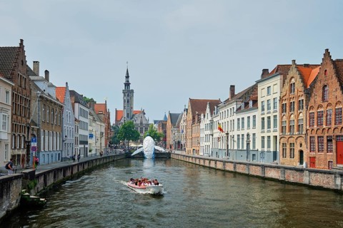 BRUGES, BELGIUM, MAY 29, 2018: Tourist boat in canal between old houses with The Bruges Whale