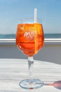 Glass of Aperol Spritz in front of the sea, horizon
