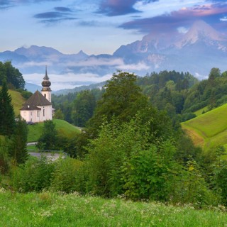 Maria Gern church in a picturesque mountain landscape, surrounded by dense green vegetation and