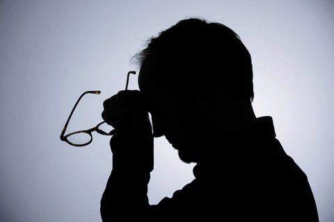 Symbolic photo on the subject of overload. Silhouette of a man rubbing his aching head. Berlin,