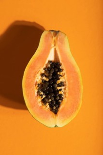 Ripe cut papaya on orange pastel background. Top view, flat lay, close up, hard light. Tropical,