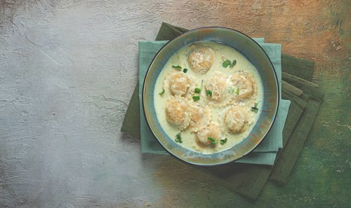 Ravioli in cream sauce, spices and herbs, top view, no people