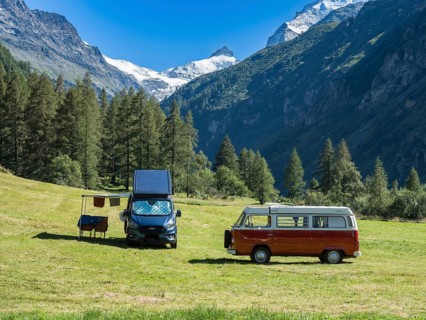 Camper vans on a small campsite, modern campervan and old VW bus, village Zinal, mountain range in