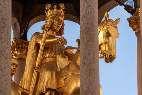 A golden sculpture of a crowned king on a horse, surrounded by columns, Golden Rider, Magdeburg,