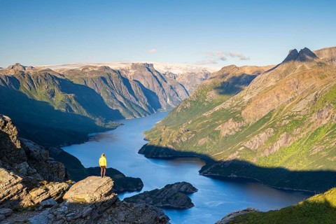 Hiker looking from Seiskallåfjellet into the Nordfjorden, Svartisen Glacier in the background,