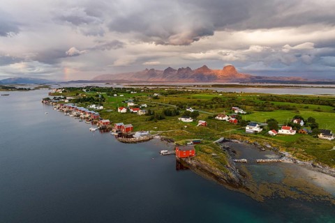 Boathouses of the village Herøy, behind the mountain range Seven Sisters, light mood, island Herøy,