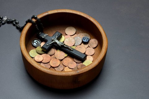 Crucifix with coins and buttons in a wooden bowl, church and money