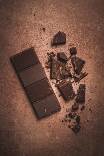 Chocolate bar, for the manufacture of confectionery, broken, crumbled, on a brown background, top