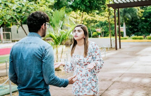 Unhappy couple standing arguing in a park. Disgusted teenage couple arguing in a park, Man and