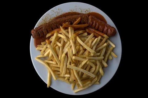 Currywurst with fries on a black background, Bavaria, Germany, Europe