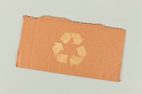 Red recycling arrow symbol on piece of cardboard