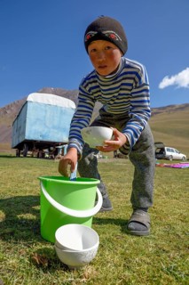 Shepherd boy scooping from a bucket of fermented mare's milk, West Karakol Valley, Tien Shan
