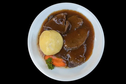 Roast pork with gravy and dumpling on a black background, Bavaria, Germany, Europe