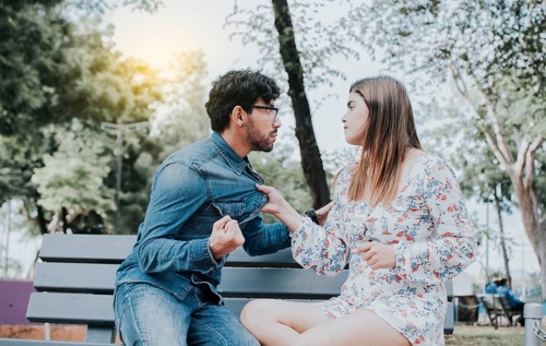 Upset couple arguing on a park bench. Young couple arguing sitting on a park bench, Concept of