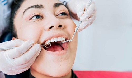 Close-up of the hands of a dentist cleaning the teeth of a female patient, Hands of a specialist