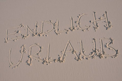 Writing in the sand "endlich Urlaub", German for "finally holidays"