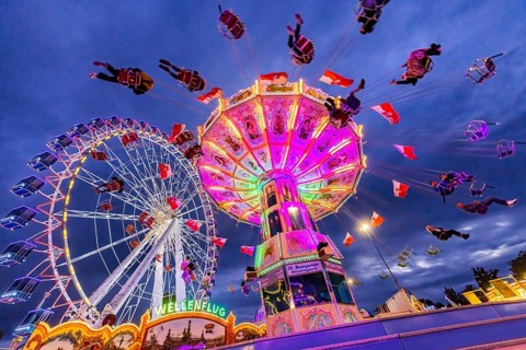 Chain carousel and Ferris wheel in the evening. 177th Cannstatter Volksfest at the Cannstatter