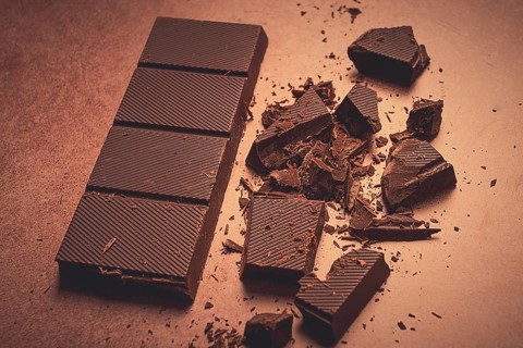 Chocolate bar, for the manufacture of confectionery, broken, crumbled, on a brown background, top