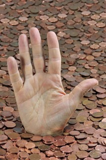 Man disappearing in euro coins while sticking hand out for help