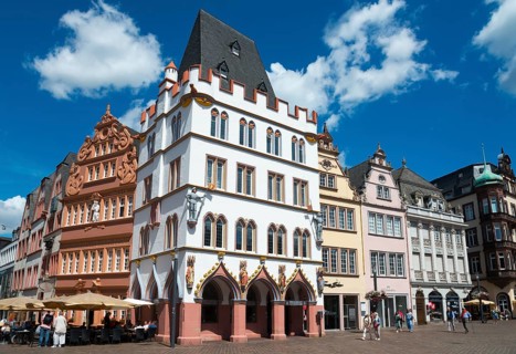 Historic old town with half-timbered houses, blue sky and cafés, animated by tourists under summer