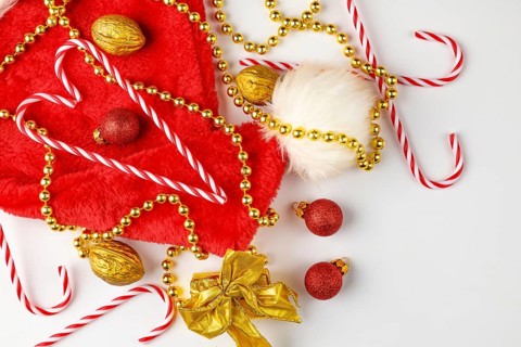 Christmas hat with candy canes, golden pearl necklace and nuts on a white background