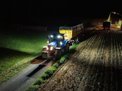 Tractor with trailer travelling along a rural road at night, maize harvest, Dachtel, Black Forest,