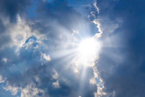 Rain clouds with sun shining through, rays of sunshine, blue sky