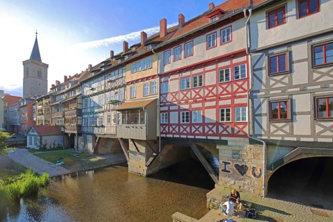Famous Krämerbrücke and Gothic Ägidienkirche with river Gera and people sitting on the bank, idyll,