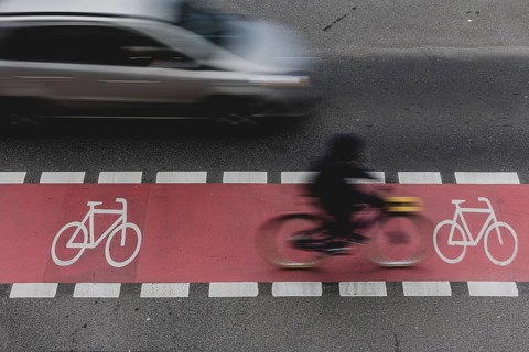 A cyclist rides on a marked cycle path on Schlossstraße and is overtaken by a car in Berlin,