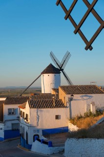 Windmill in front of white houses at sunset in a rustic village with warm light and blue accents