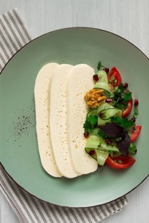 Sliced Imeruli cheese, Georgian cheese, with vegetables, top view, no people