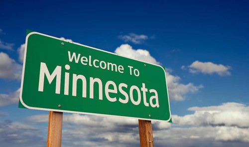 Welcome to minnesota green road sign over blue sky with some clouds