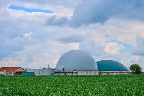 Modern biogas plant in the middle of green fields under a cloudy blue sky, summer, Middle