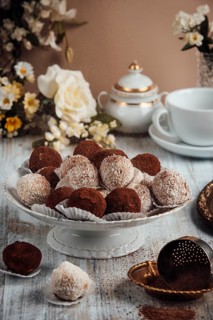 Elegantly arranged tiramisu, chocolates on a porcelain plate next to flowers and a cup