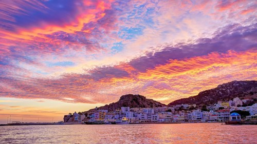 Atmospheric coastal panorama at sunrise with vivid colours in the sky and a small town by the sea,