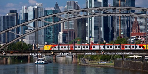 Main with regional railway on the Deutschherrnbrücke and a cargo ship in front of the skyline of