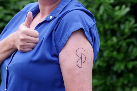 Tattoo, Upper arm, Woman, Organ donation, Tattoo, Skin, A woman shows the tattooed symbol for organ