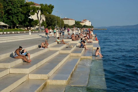 Visitors basking in the evening sun at the Sea Organ by architect Nikola Bašic, Zadar, Dalmatia,