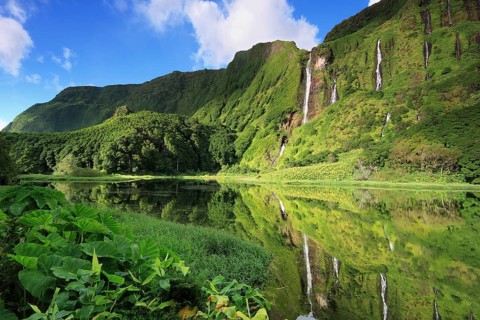Waterfalls on the forested slope of a volcano reflected in a lake, Ilha das Flores, Azores,
