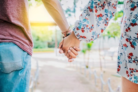 Close up of couple holding hands outdoors, Close up of young couple walking holding hands. Close-up