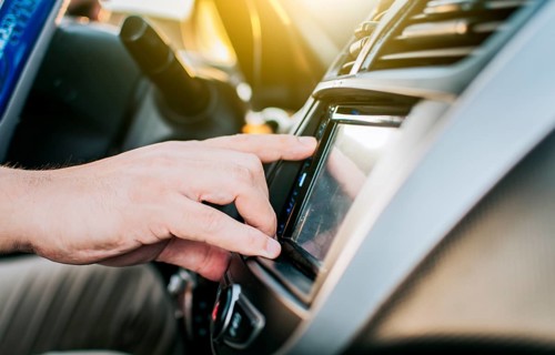 Close up of hands changing the car radio station. Concept of driver tuning the radio. Driver man