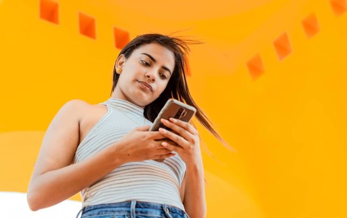 Portrait of attractive latin girl messaging on cell phone. Low angle of a beautiful Latin girl
