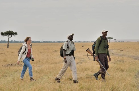 Tourist with armed guard and guide on a walking safari, Massai Mara, Serengeti, Rift Valley