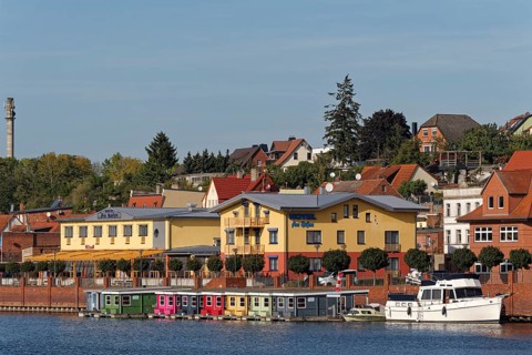 Boathouses on the banks of the Havel River in front of a hotel in the Hanseatic town of Havelberg