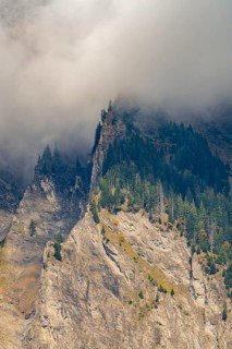 Misty mountain landscape with steep cliffs and dense forest, mysterious atmosphere, Brienz,
