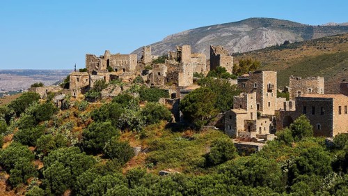 Historic stone buildings of a mountain village surrounded by trees and vast landscape, Vathia,