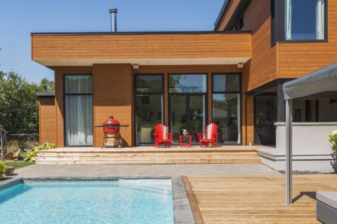 Rear of modern cube style home with stained horizontal wood cladding, in-ground swimming pool and