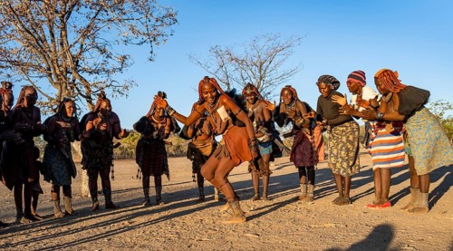 Group of traditional Himba woman standing in a semi-circle, clapping and dancing, music and dance,